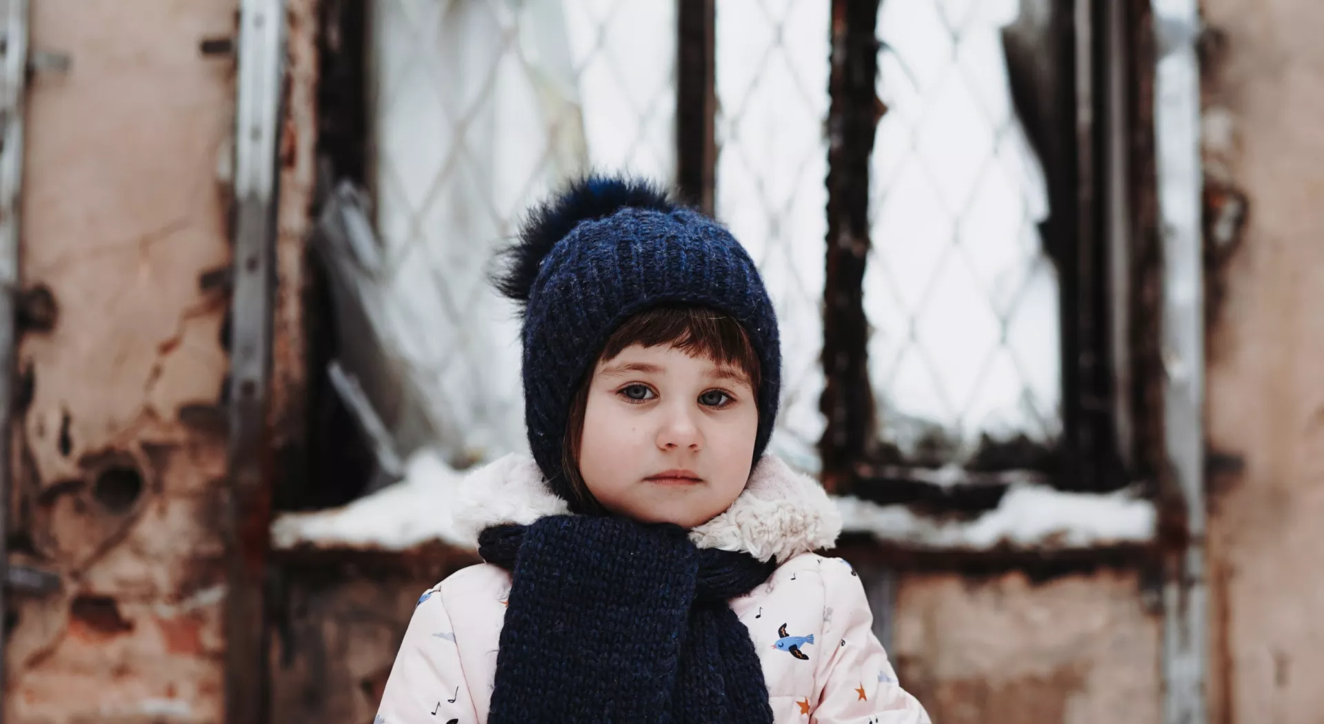 ZOA Jahresbericht: Mädchen aus der Ukraine vor einem zerstörten Haus im Winter