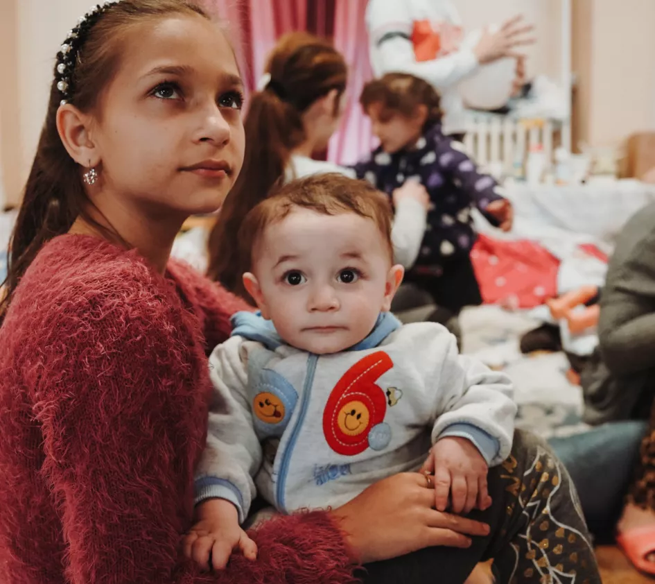 Schneller über die Grenze: Ukrainisches Mädchen mit einem Baby auf dem Arm in einem Auffanglager