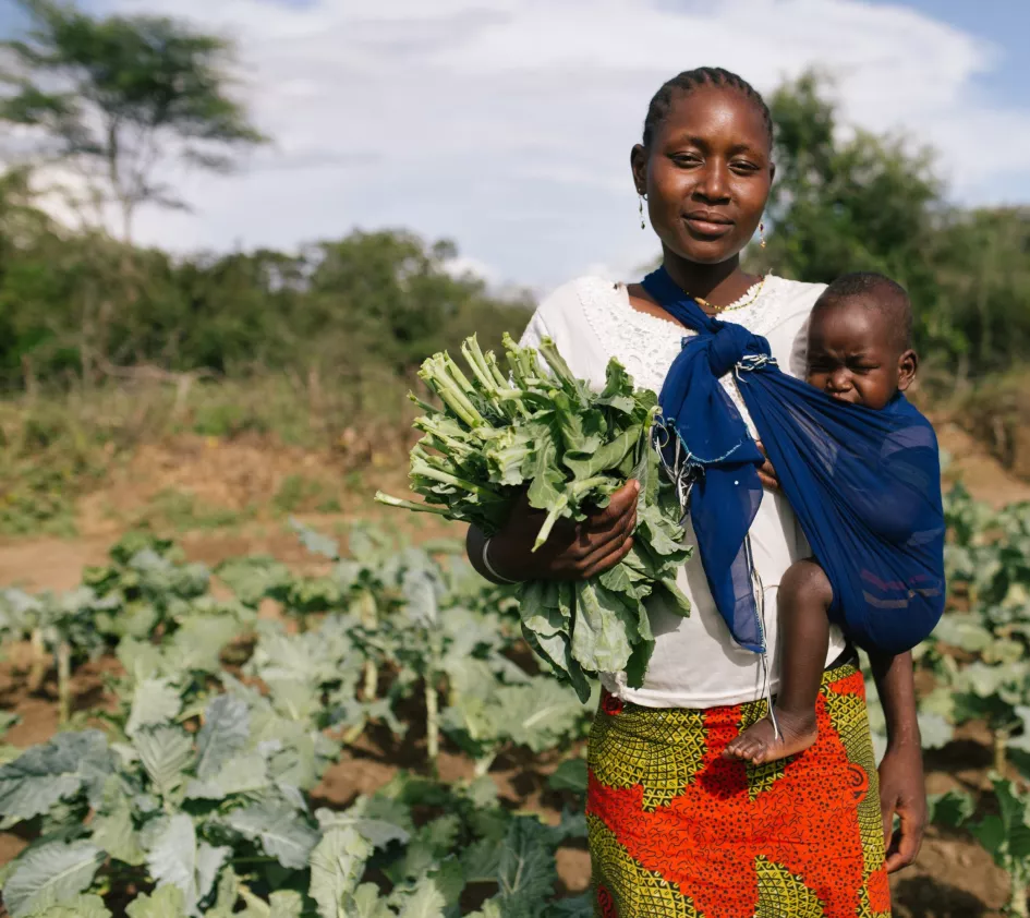 Weltflüchtlingstag: Frau in Uganda mit ihrem Kind in ihrem Feld