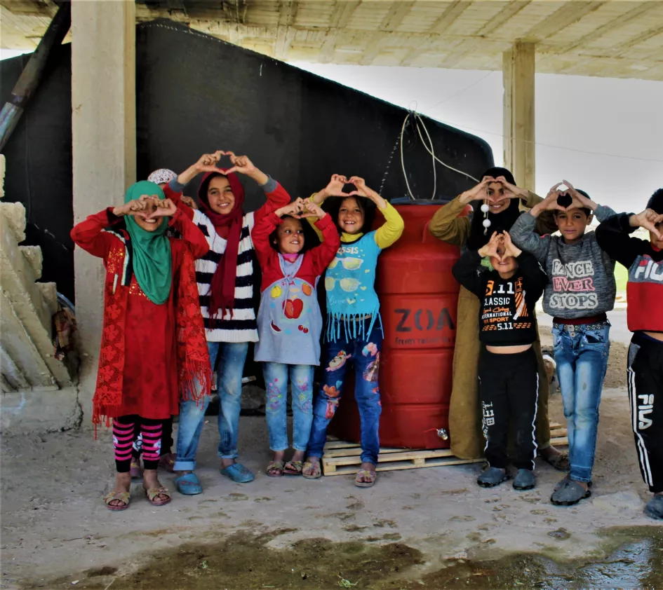 Rückblick 2021: Kinder zeigen Herzen mit ihren Herzen an einem ZOA-Wassertank