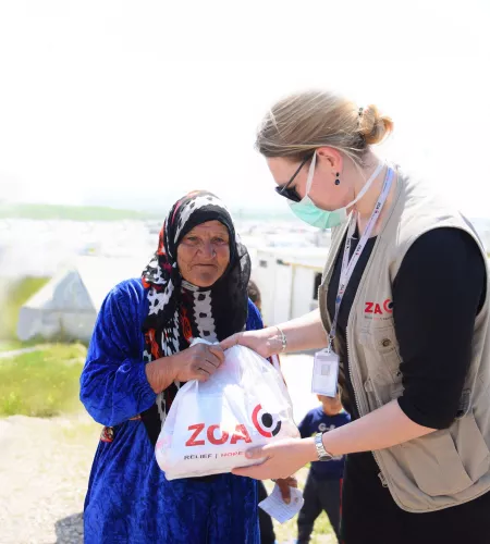 Engagiert für Flüchtlinge: ZOA Mitarbeiterin Esther gibt eine Tüte an eine Frau im Irak