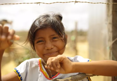 Jahresbericht 2021: Kolumbianisches Mädchen schaut durch einen Stacheldrahtzaun