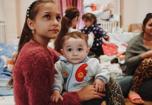 Schneller über die Grenze: Ukrainisches Mädchen mit einem Baby auf dem Arm in einem Auffanglager
