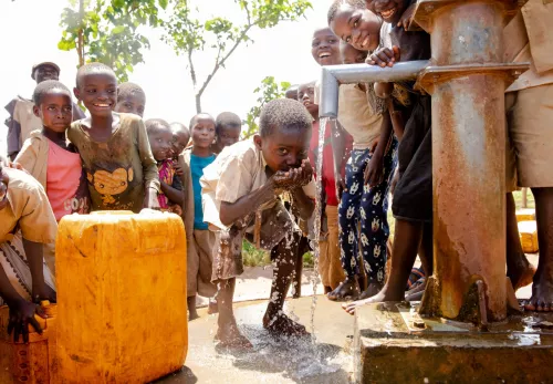 Junge schöpft Wasser von einem Wasserhahn
