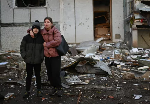 Flüchtlingshilfe Ukraine: Frau mit ihrem Sohn vor Haustrümmern