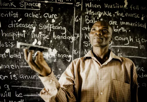 Weshalb ZOA in Bildung investiert: dunkelhäutiger Mann vor einer vollgeschriebenen Tafel