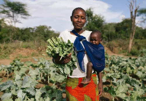 Weltflüchtlingstag: Frau in Uganda mit ihrem Kind in ihrem Feld