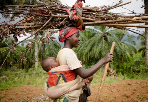 Burundi: Frau mit Kind trägt Äste auf dem Kopf