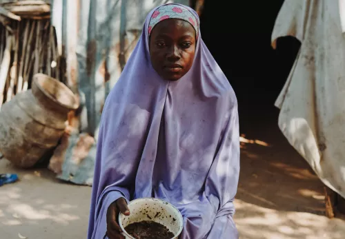 Habiba zeigt ihren vier Kindern, was sie für die nächsten Tage an Lebensmitteln übrig hat. In der Pfanne befindet sich eine handvoll Weizenbrei.