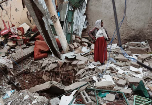 Frau steht neben ihrem zerstörten Haus in Tigray