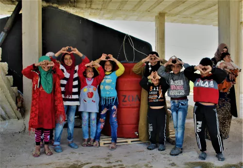 Rückblick 2021: Kinder zeigen Herzen mit ihren Herzen an einem ZOA-Wassertank